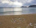 Haert made form pebbles on sand beach with sea and sky with dramatic clouds with sun rays beams and view on porto timony Royalty Free Stock Photo