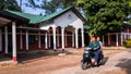 A man on a motorbike rides past the old vintage colonial architecture of a building