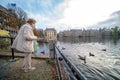 The Hague, The Netherlands - November 10, 2020: Cityscape of the Hague. Happy elderly senior retired woman feeds birds