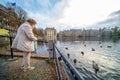 The Hague, The Netherlands - November 10, 2020: Cityscape of the Hague. Happy elderly senior retired woman feeds birds