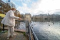 The Hague, The Netherlands - November 10, 2020: Cityscape of The Hague. Happy elderly senior retired woman feeds birds. She wears