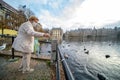 The Hague, The Netherlands - November 10, 2020: Happy elderly senior retired woman with mouth mask. feeds birds bread