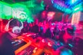 Dj in booth in night club with visitors dancing in blurry way