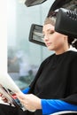 Haidressing salon. Woman dying hair reading magazine. Modern equipment.