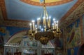 The large chandelier with candle-shaped electric lamps hangs from the ceiling in the middle of the main hall of the Russian