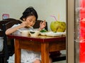 HAIKOU, CHINA - MAR 2 2019 Ã¢â¬â Young Asian Chinese girl enjoys a healthy meal of rice, vegetables, and coconut water. To