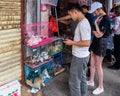 HAIKOU, HAINAN, CHINA - MAR 2 2019 - Young Asian Chinese couple browse a pet shop with animals cramped in small cages