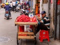 HAIKOU, HAINAN, CHINA - MAR 2 2019 - Street vendor smokes a cigarette while selling tropical wax apples / Jambu fruit