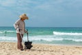 Hainan Island, Sanya, China - May 16, 2019: A cleaning lady picks up trash on Hainan Beach with special handy forceps