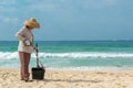 Hainan Island, Sanya, China - May 16, 2019: A cleaning lady picks up trash on Hainan Beach with special handy forceps Royalty Free Stock Photo