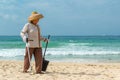 Hainan Island, Sanya, China - May 16, 2019: A cleaning lady picks up trash on Hainan Beach with special handy forceps Royalty Free Stock Photo