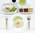 Hainanese chicken rice with cucumber on dish and hainanese chicken on plate with sauce .