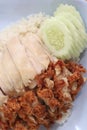 Hainanese chicken rice with Roasted Chicken on wooden table.Hainanese chicken rice is a dish of poached chicken and seasoned rice Royalty Free Stock Photo