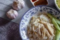 Hainanese chicken rice served in a Chinese style dish with soy sauce and broth on a gray table