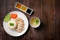 Hainanese chicken rice with soup and three sauces on dark wood table texture copy space