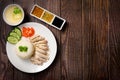 Hainanese chicken rice with soup and three sauces on dark wood table texture with copy space