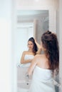 Hair and body care. Woman touching wet hair and smiling while looking in the mirror. Portrait of girl  in bathroom applying condit Royalty Free Stock Photo