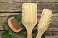 Hair brushes, comb and monstera leaf on wooden table, flat lay Royalty Free Stock Photo