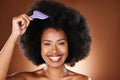 Hair care, beauty and black woman with comb in afro smiling in studio on brown background. Fashion, hair salon and face Royalty Free Stock Photo