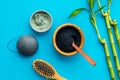 Hair care, hair spa. Cosmetics based on bamboo charcoal powder near comb on blue background top view