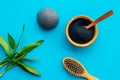 Hair care, hair spa. Cosmetics based on bamboo charcoal powder near comb on blue background top view