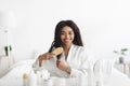 Daily hair care at home during covid-19 lockdown. Happy african american lady combing her curly hair in bedroom Royalty Free Stock Photo