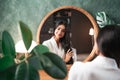 Hair care and self-care with beautiful Indian woman looking in mirror touching her healthy long hair Royalty Free Stock Photo