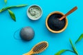 Hair care, hair spa. Cosmetics based on bamboo charcoal powder near comb on blue background top view