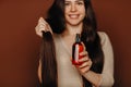 Hair-care. Young satisfied woman holding long healthy brown hair, advertising shampoo or conditioner