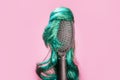 Hair coloring and dye. Comb with turquoise wig on pink background, like woman's head. Hairstyle and beauty salon