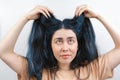 Hair coloring. A young Caucasian woman in a beige t-shirt, anxiously examines her long blue hair, looking up. White background Royalty Free Stock Photo