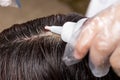 Hair dresser applying chemical hair color dye onto hair roots