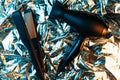 Hair dryer and hair straightener in neon lights on the foil with shiny crumpled surface background. 80s and 90s style.