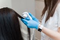 Hair examination with a trichoscope. Trichologist examines the long hair of a girl