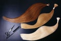 Hair extensions of three colors on a dark background with Scissors and comb. copyspace top view.