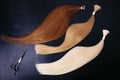 Hair extensions of three colors on a dark background with scissors. copyspace. top view. Royalty Free Stock Photo