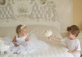 Hair and inspiration. Page boy with blond hair hold wedding bunch. Little flower girl wear tiara crown and hairstyle