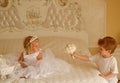 Hair and inspiration. Page boy with blond hair hold wedding bunch. Little flower girl wear tiara crown and hairstyle