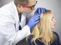 A doctor trichologist conducts a study of the hair of a blonde. Alopecia treatment. Hair loss, alopecia, itching, burning in the