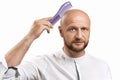 Hair loss concept. Young bald man with a hairbrush on a white background. Royalty Free Stock Photo