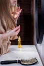 Hair loss. Depressed young woman looking at her hairbrush and expressing negativity while standing against mirror Royalty Free Stock Photo