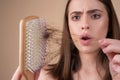 Hair loss. Woman is upset of hair loss. Portrait of sad girl with problem hair, isolated. Worried girl holding long