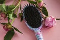 Hair massage comb brush with peony flowers  on pink pastel copy space background. Minimalistic flat lay Royalty Free Stock Photo