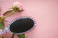 Hair massage comb brush with peony flowers  on pink pastel copy space background. Minimalistic flat lay Royalty Free Stock Photo