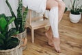 Hair Removal concept, depilation cream. Young woman in white towel applying shaving cream on her legs in home bathroom with green Royalty Free Stock Photo