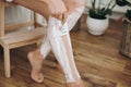 Hair Removal with depilation cream concept. Young woman in white towel applying shaving cream on her legs and holding plastic Royalty Free Stock Photo