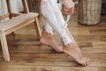 Hair Removal with depilation cream concept. Young woman in white towel applying shaving cream on her legs and holding plastic Royalty Free Stock Photo