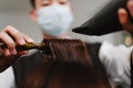 Hair salon concept a male hairstylist using a comb to grab a lock of hair and using hair dryer for drying and straightening