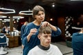 Hair salon for men. Young caucasian man getting new haircut in the modern barbershop. Professional barber girl doing Royalty Free Stock Photo