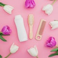 Hair styling concept with shampoo, combs and tulips flowers on pink background. Flat lay, top view Royalty Free Stock Photo